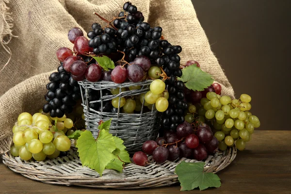 Assortment of ripe sweet grapes in basket, on grey background — Stock Photo, Image