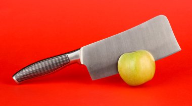 Yeşil elma ve kırmızı bir arka plan üzerinde bıçak