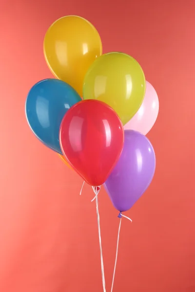 Kleurrijke ballonnen op rode achtergrond — Stockfoto