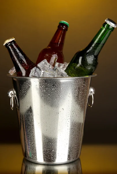 Botellas de cerveza en cubo de hielo sobre fondo amarillo darck —  Fotos de Stock