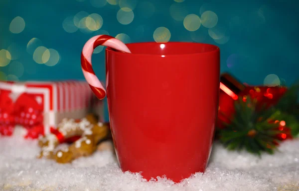 Bevanda calda gustosa in tazza rossa con caramelle di Natale su sfondo blu — Foto Stock