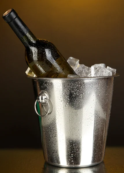 Botella de vino en cubo de hielo sobre fondo amarillo darck —  Fotos de Stock