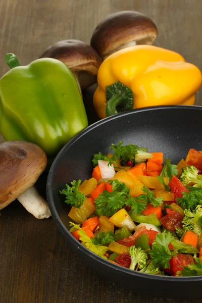 In Scheiben geschnittenes frisches Gemüse in Pfanne mit Gewürzen und Zutaten auf Holztisch — Stockfoto