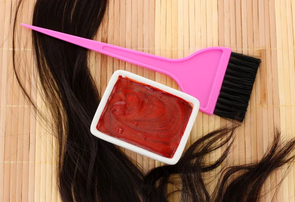 Hair dye in bowl and brush for hair coloring on beige bamboo mat, close-up — Stock Photo, Image