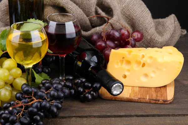 Bottiglie e calici di vino, formaggio e uva su fondo grigio — Foto Stock