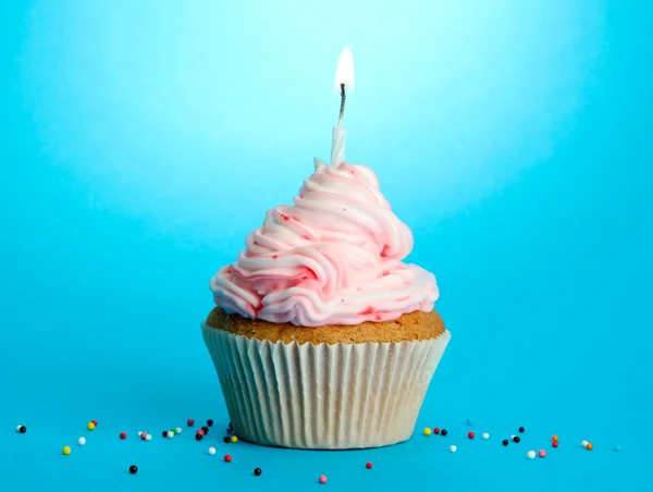 Cupcake de aniversário saboroso com vela, no fundo azul — Fotografia de Stock