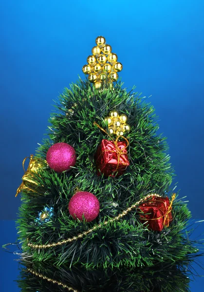 Geschmückter künstlicher Weihnachtsbaum auf blauem Hintergrund — Stockfoto