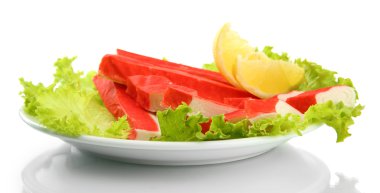 Yengeç sopalarla marul yaprakları ve plaka üzerinde beyaz izole limon