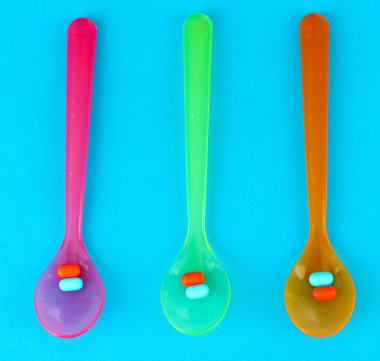 plastik kaşık ile mavi arka plan üzerinde renkli hapları