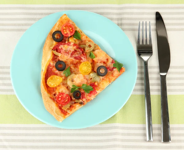 Assiette avec une tranche de délicieuse pizza sur la nappe gros plan — Photo