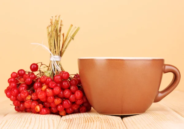 Tee mit rotem Viburnum auf Tisch auf beigem Hintergrund — Stockfoto