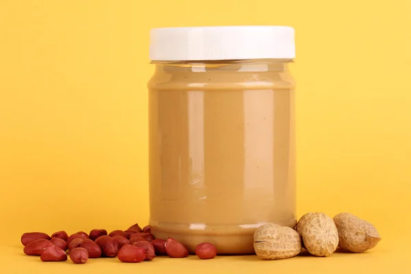 Delicious peanut butter in jar of peanut near on yellow background — Stock Photo, Image