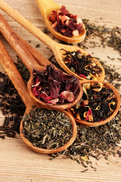 Assortment of dry tea in spoons, on wooden background — Stock Photo, Image