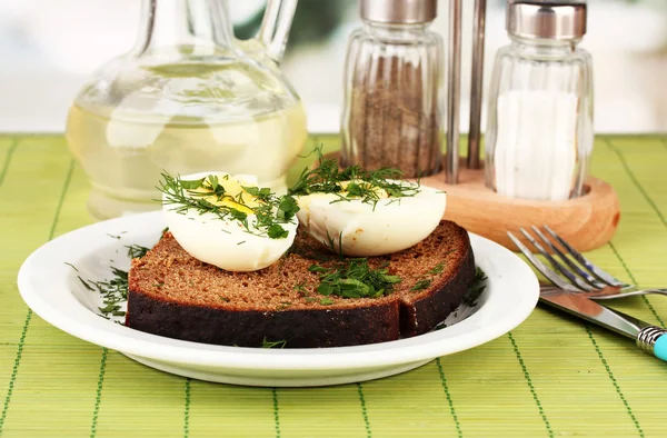 Boiled eggs on dark bread on green background — Stock Photo, Image