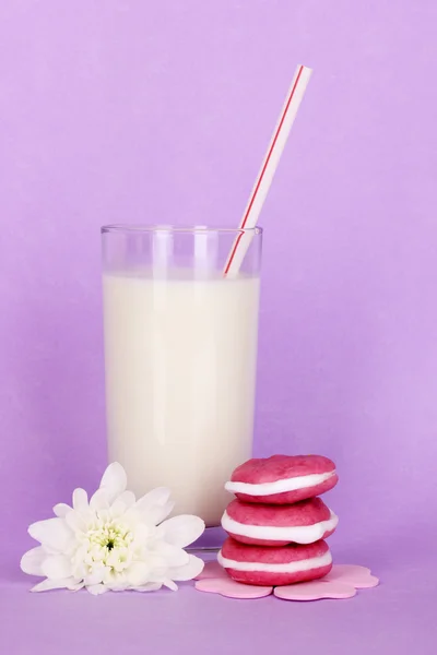 Glass of fresh new milk with cakes on purple background — Stock Photo, Image