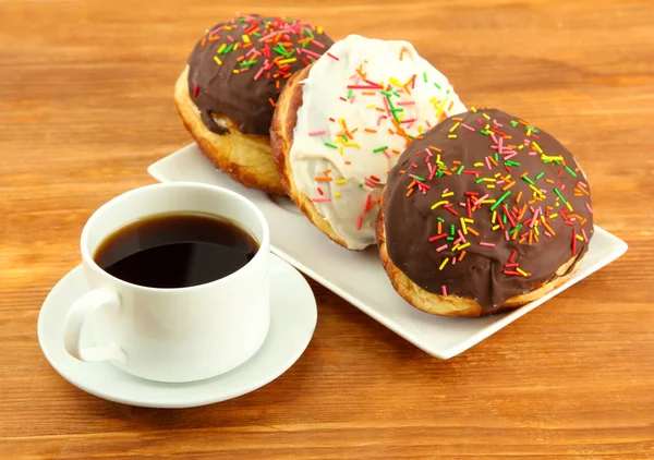 Sabrosas rosquillas en la placa de color sobre fondo de madera — Foto de Stock