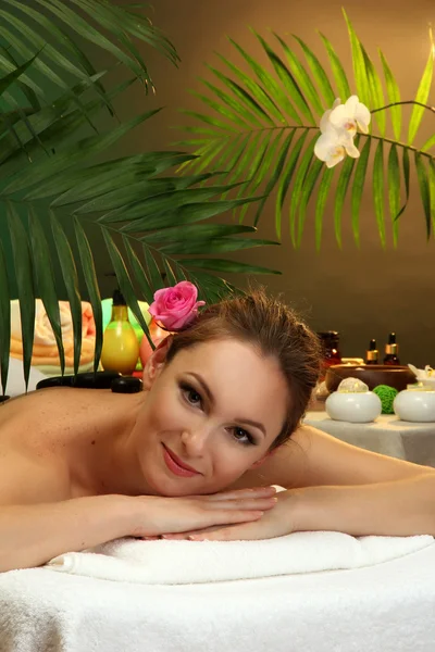 Hermosa joven en el salón de spa con piedras de spa, sobre fondo verde — Foto de Stock