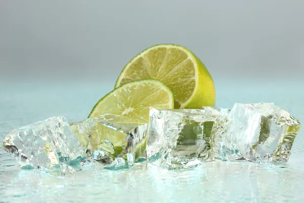 Eiswürfel mit Limette auf hellblauem Hintergrund — Stockfoto