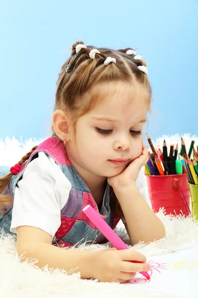 Mignonne petite fille jouant avec des crayons multicolores, sur fond bleu — Photo