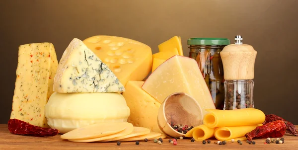 Varios tipos de queso sobre mesa de madera sobre fondo marrón —  Fotos de Stock