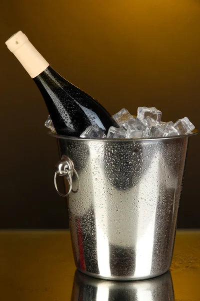 Bottle of wine in ice bucket on darck yellow background — Stock Photo, Image