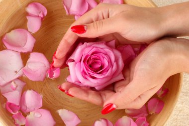 woman hands with wooden bowl of water with petals clipart