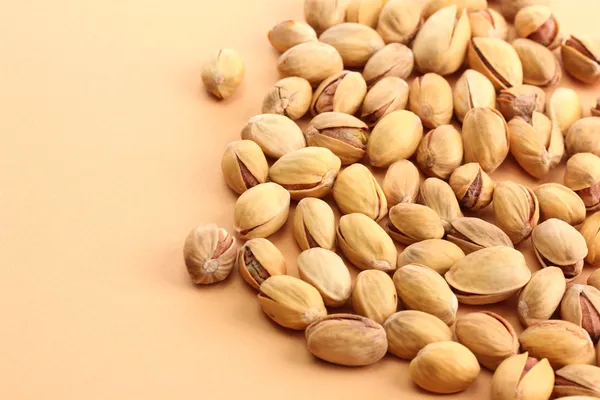 Tasty pistachio nuts, on beige background — Stock Photo, Image