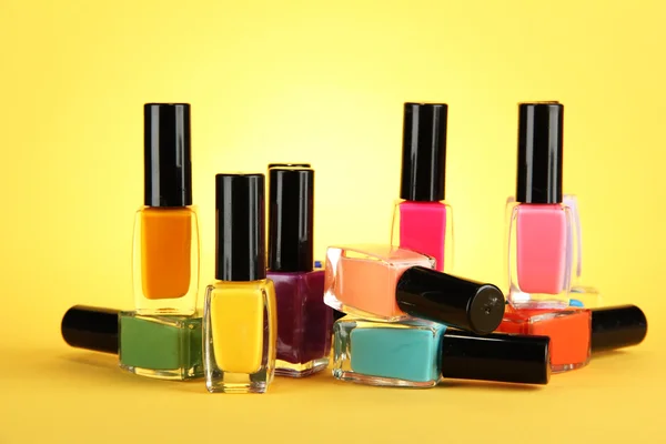 Grupo de esmaltes de uñas brillantes, sobre fondo amarillo —  Fotos de Stock