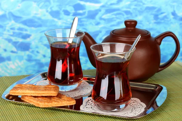 Glass of Turkish tea and kettle on color background — Stock Photo, Image