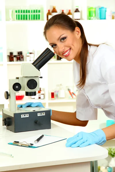 Un jeune scientifique se penche sur le microscope en laboratoire — Photo