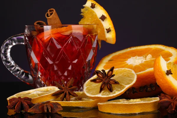 Fragrant mulled wine in glass with spices and oranges around on purple background — Stock Photo, Image