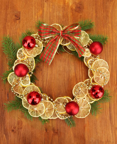 Corona de Navidad de limones secos con abeto y bolas, sobre fondo de madera — Foto de Stock