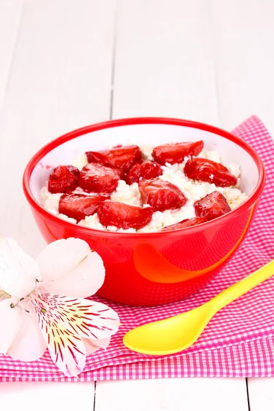 Queso de cabaña en tazón rojo con fresas en rodajas sobre mesa de madera blanca —  Fotos de Stock