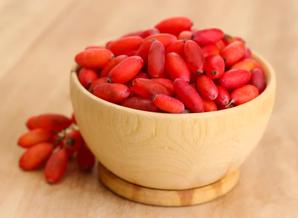 Ripe barberries in wooden bowl, on wooden background — Stock Photo, Image