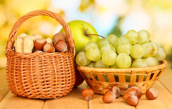 Виноград в корзине с орехами на деревянном столе — стоковое фото