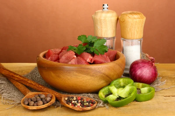 Ruwe rundvlees met kruiden en specerijen op houten tafel op bruine achtergrond — Stockfoto