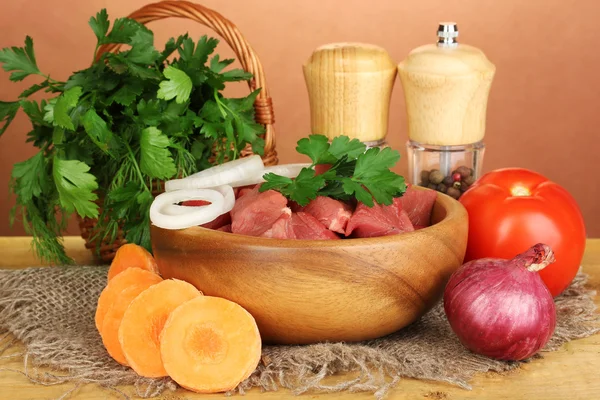 Carne di manzo cruda con erbe e spezie sul tavolo di legno su sfondo marrone — Foto Stock