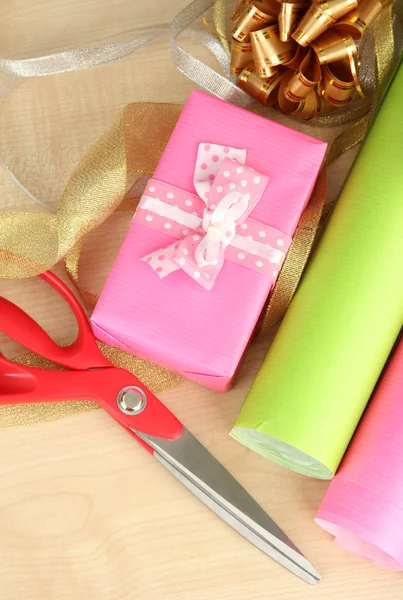 Rolos de papel de embrulho de Natal com fitas, arcos em fundo de madeira — Fotografia de Stock