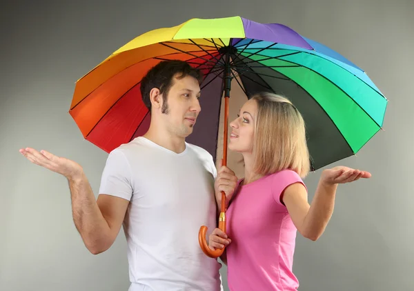 Casal amoroso com guarda-chuva no fundo cinza — Fotografia de Stock