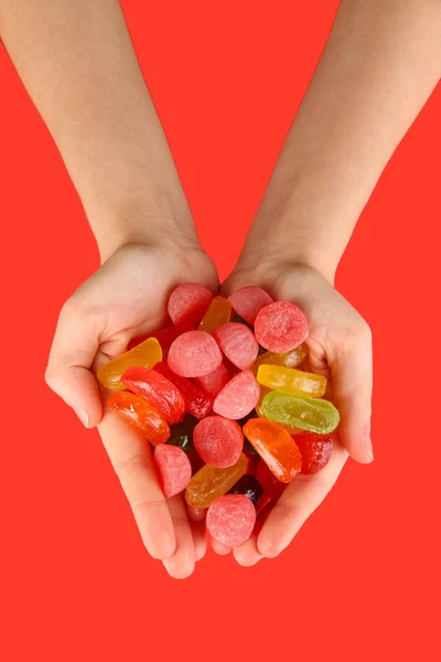 Mains pleines de bonbons sur fond rouge — Photo