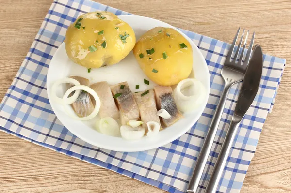 Schüssel mit Hering und Kartoffeln auf Teller auf Holztisch in Großaufnahme — Stockfoto