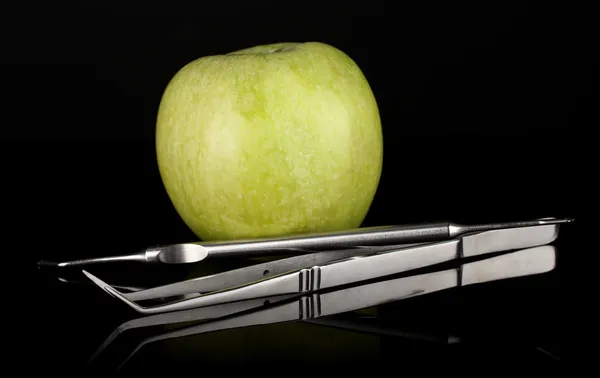 Dentální nástroje izolovaných na černé a zelené jablko — Stock fotografie