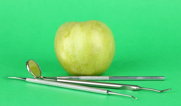 Grüner Apfel und zahnärztliche Werkzeuge auf farbigem Hintergrund — Stockfoto