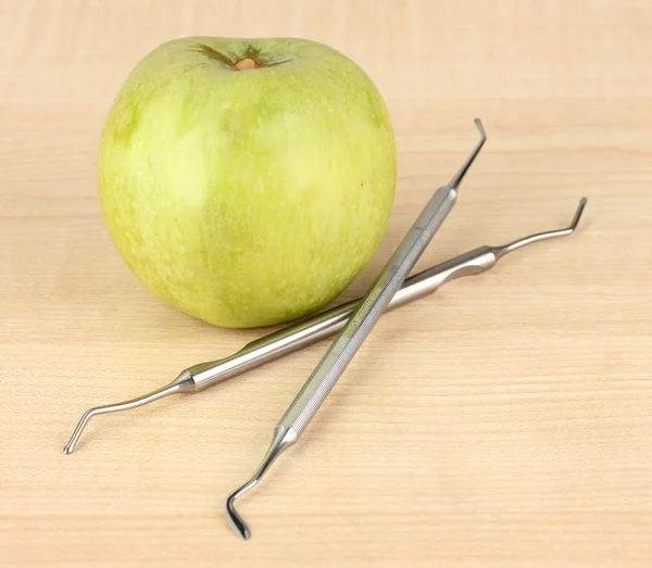 Grüner Apfel und zahnärztliche Instrumente auf hölzernem Hintergrund — Stockfoto