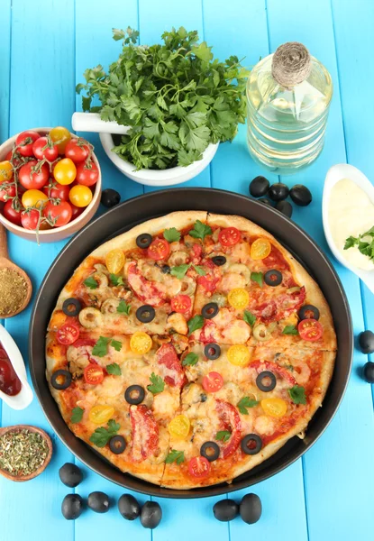 Kleurrijke samenstelling van heerlijke pizza, groenten en specerijen op blauwe houten achtergrond close-up — Stockfoto