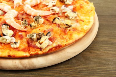 ahşap arka plan üzerinde durmak üstünde deniz ürünleri ile lezzetli pizza