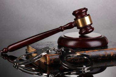 Tokmak, kelepçe ve gri arka plan üzerine hukuk kitabı