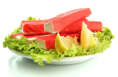 Yengeç sopalarla marul yaprakları ve plaka üzerinde beyaz izole limon