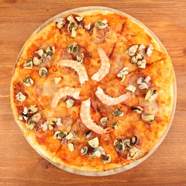 Смачна піца з морепродуктами на підставці на дерев'яному фоні — стокове фото