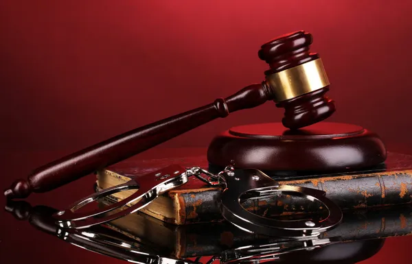 Gavel, handcuffs and book on law on red background — Stock Photo, Image